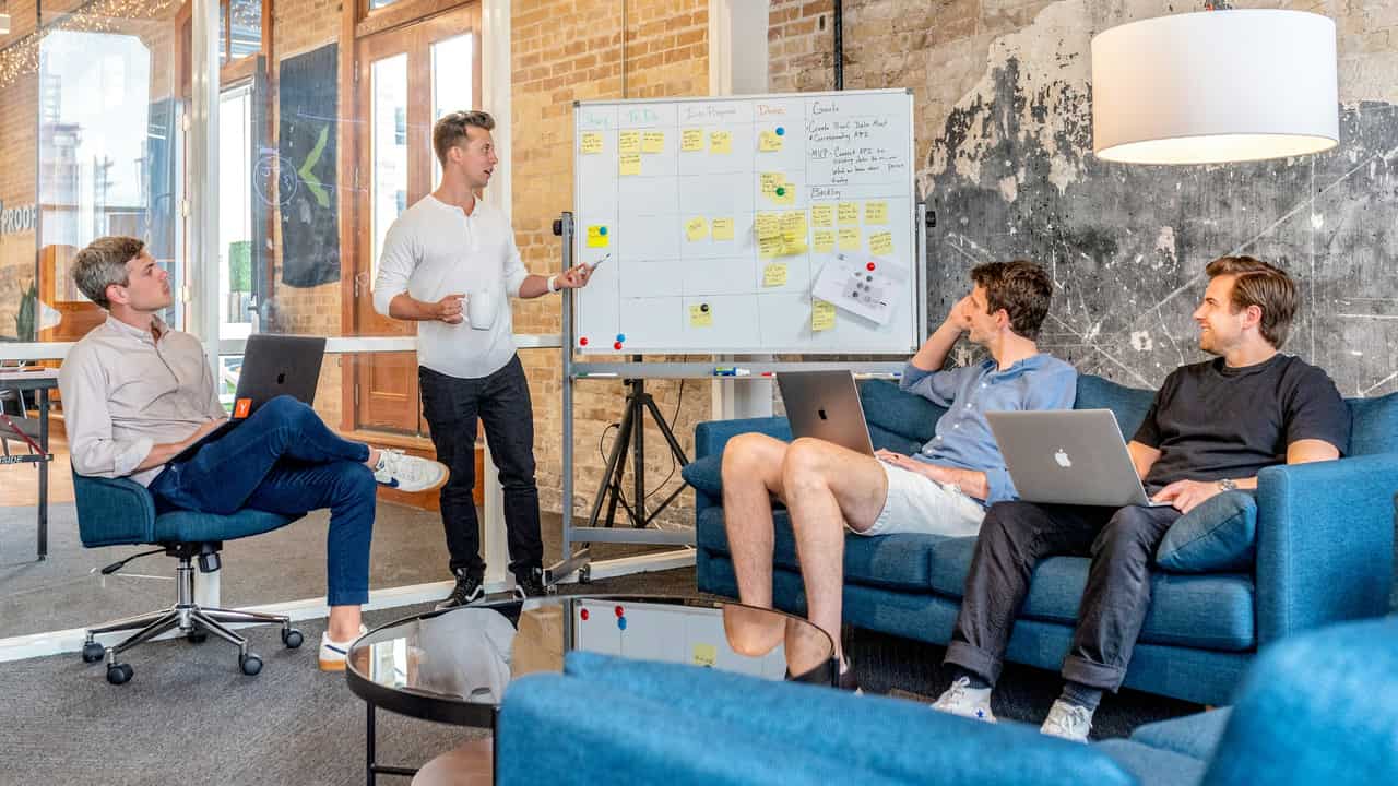 Reunión de equipo en un espacio diáfano de estilo industrial con sofás y portátiles