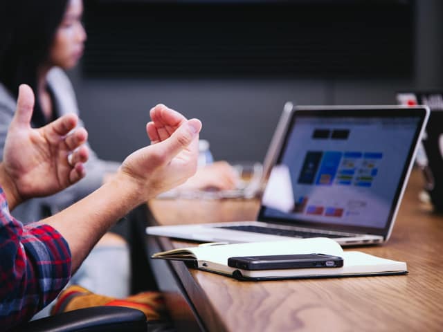Reunión de trabajo con varias personas gesticulando alrededor de un portátil
