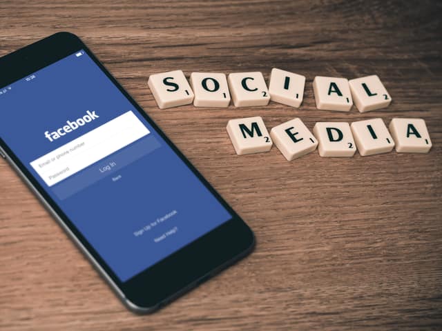Teléfono móvil sobre una mesa junto a letras de madera que forman la palabra social media