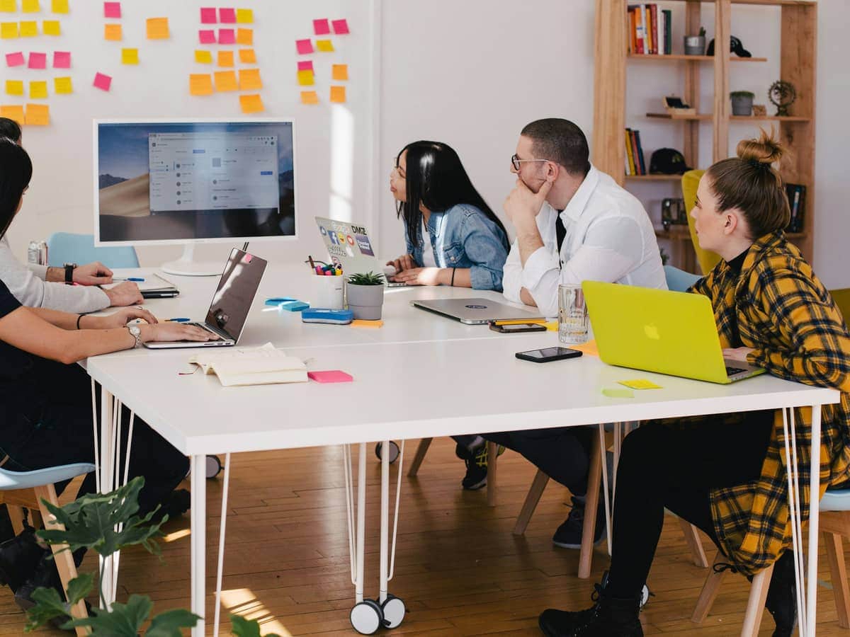 Equipo reunido alrededor de una mesa de trabajo blanca con varios portátiles