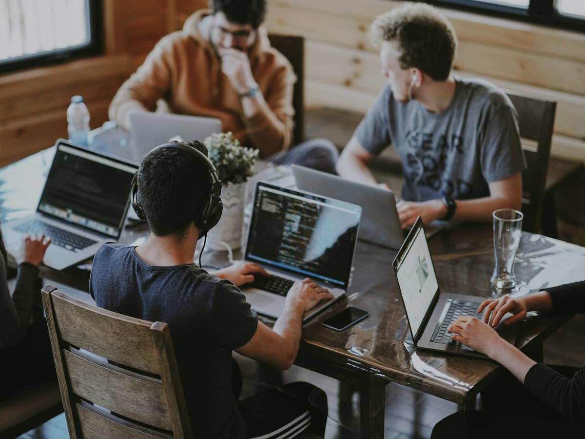 Varias personas trabajando con portátiles en una mesa larga compartida